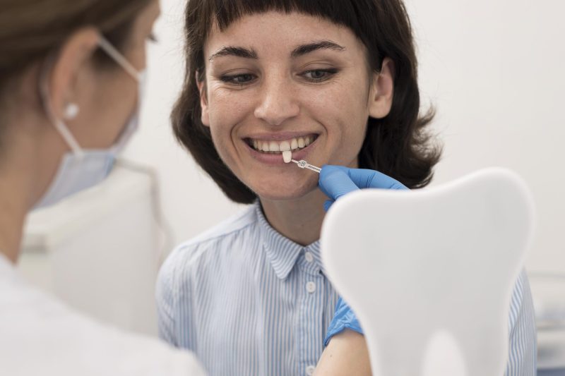 young-female-patient-looking-mirror-check-teeth-matching-before-dental-procedure